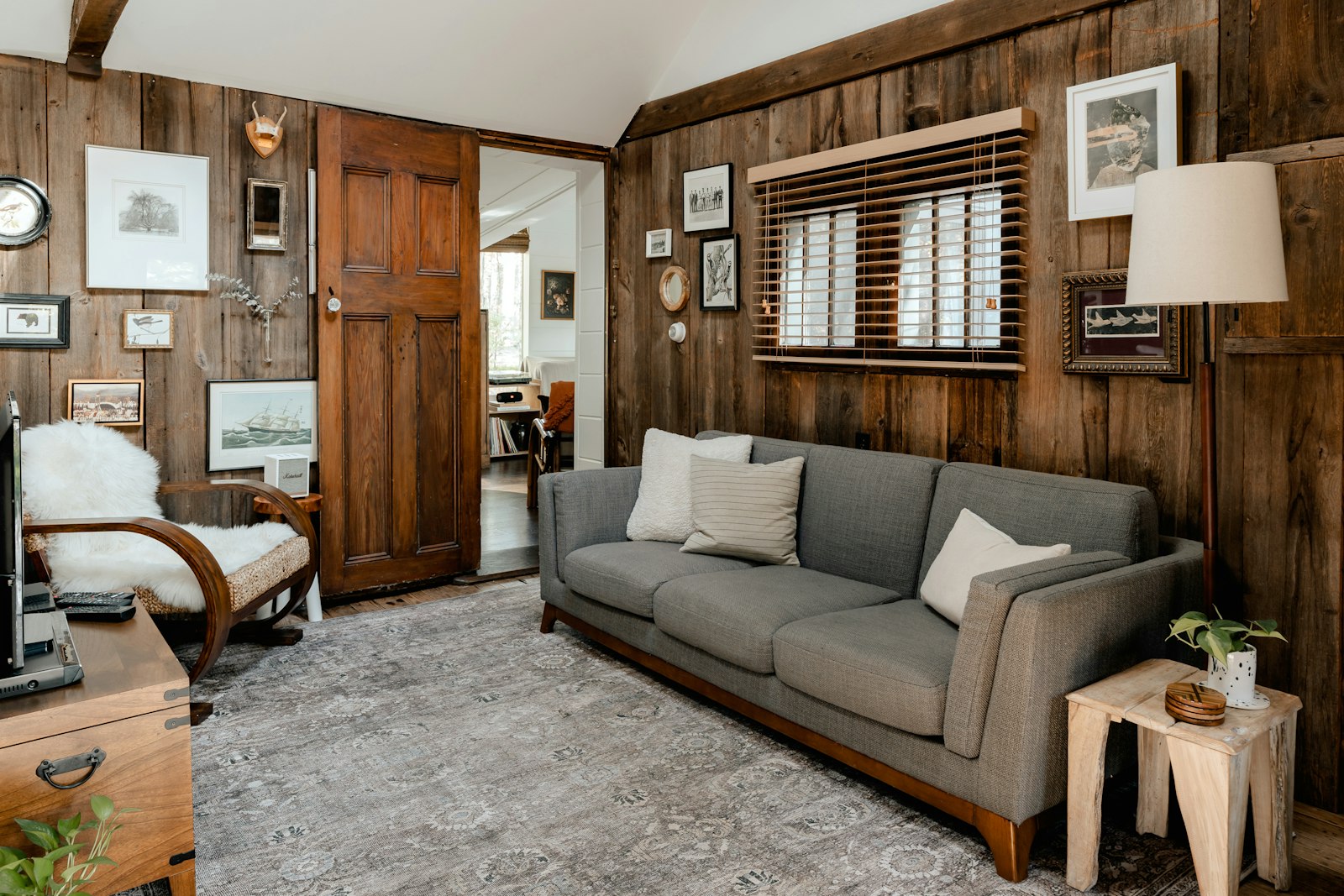 A warm, dimly lit living room with wood paneling at dusk
